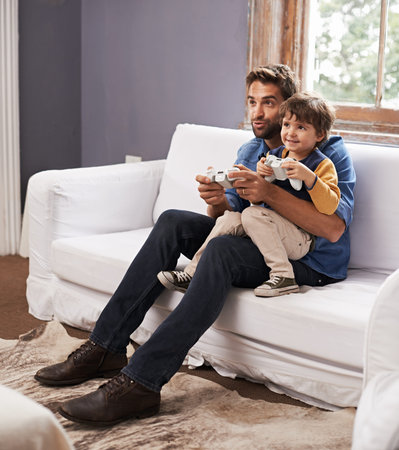Guys and their games. A handsome father and his cute son playing a video game together.