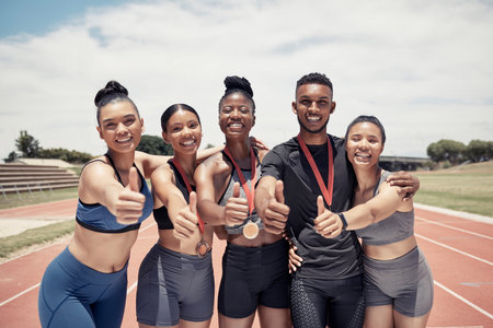 Team, thumbs up and sport winner with medal, runner and happy in portrait, success and win on race track. Young black man, diversity and fitness, athlete winning with exercise and collaboration.の写真素材