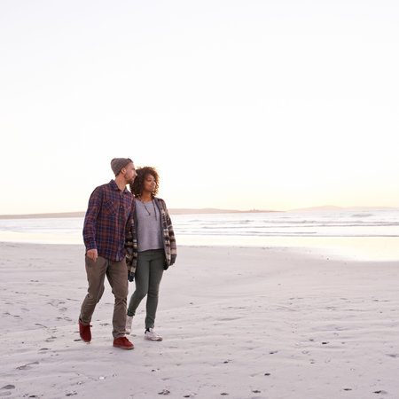 Look at the sunset. a young couple enjoying a walk on the beach.