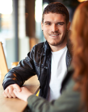 Someones a little smitten. A cropped shot of a young affectionate couple on a coffee date.の写真素材