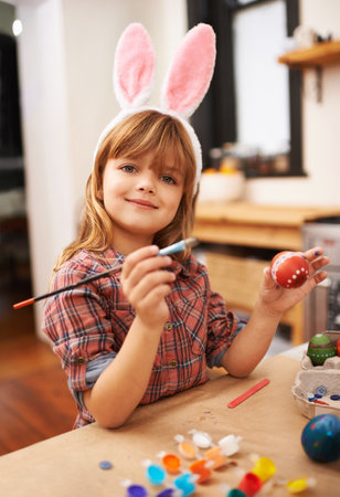 Easter bunny artwork. a little girl wearing bunny ears while painting an easter egg.の写真素材
