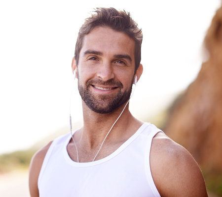 Time for a relaxing run. a handsome young man standing outdoors with earphones.
