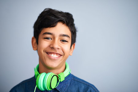 Hes already got style. A cute young preteen boy standing and smiling against a grey background.