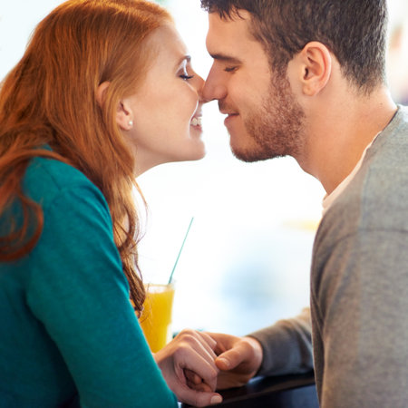 In their own little world. a happy young couple being affectionate while sitting at a cafe.の写真素材