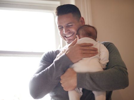 Gotta love that beautiful baby smell. a young father lovingly embracing his daughter.の写真素材
