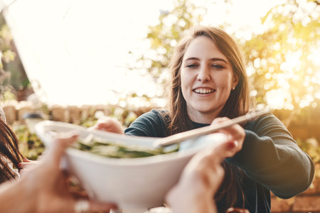 Food, salad and healthy eating outdoor with woman giving or serving bowl with vegetables on patio for Christmas or thanksgiving lunch or dinner. Family or friends together to eat at home celebrationの写真素材