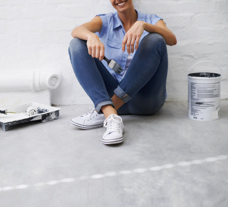 Its decorating down time. a woman sitting on a floor taking a break from painting.の写真素材