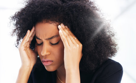 Headache, stress and burnout with a business black woman struggling with mental health issues while working in her office. Compliance, face and pain with a female employee suffering from a migraineの写真素材