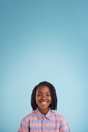 Youthful confidence. A portrait of a happy young boy standing against a blue background.の写真素材