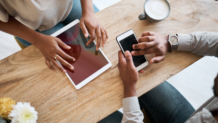 Hands, tablet and phone with a coffee shop business team working together online closeup from above. Marketing, ecommerce and remote work with a man and woman employee at work in an internet cafeの写真素材