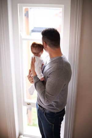 It doesnt get any better than this. a young father standing at a window holding his adorable daughter.の写真素材