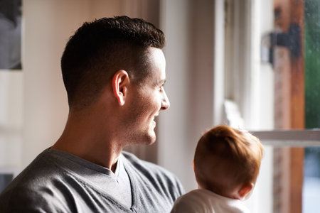 Its all about these moments. a young father standing at a window holding his adorable daughter.の写真素材