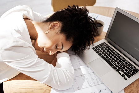 Black woman, laptop and burnout for startup company, sleeping and overworked at desk. Female entrepreneur, African American girl or business pressure, tired or depressed for work, frustrated or sleepの写真素材