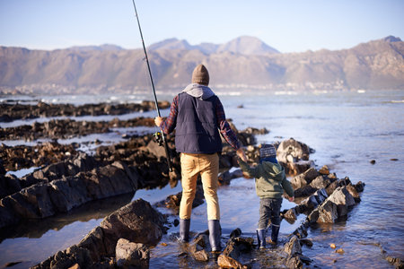 Waiting for the perfect catch. a father and son fishing by the sea.の写真素材