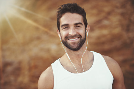 Running is more than exercise, its a way of life. Portrait of a young man listening to music on earphones while out for a run.の写真素材