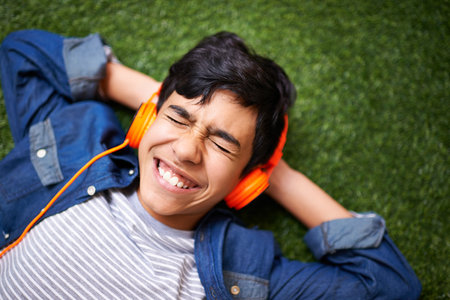 Loving this song. A young boy relaxing on the lawn and listening to music.の写真素材