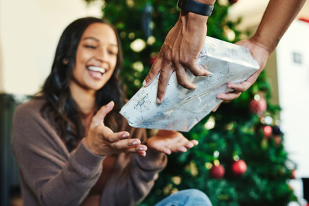 Couple, bonding or hands and christmas gift box in house or home living room for holiday celebration, festive vacation or surprise giving. Smile, happy or xmas woman with present from man in Portugalの写真素材