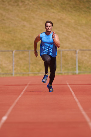 Holding nothing back. Action shot of a young male athlete running on a track.の写真素材