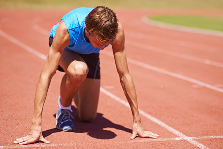 Ready for the race. a young male athlete at the start of a track race.