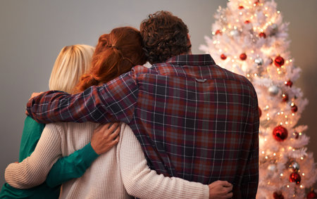 Treasured moments by the tree. Rear view shot of three friends bonding by a Christmas tree.の写真素材