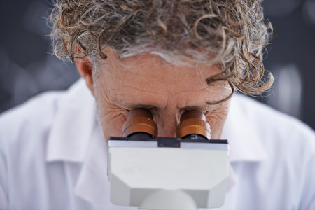 Intriguing observations. A cropped front view shot of a mature scientist using a microscope in his...