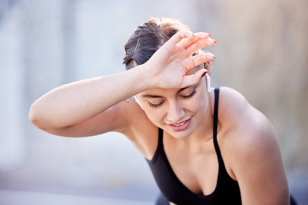 Fitness music, sweat and woman tired after outdoor running, cardio workout or marathon race training. Radio podcast, wellness and exhausted athlete runner with fatigue after sports performance actionの写真素材