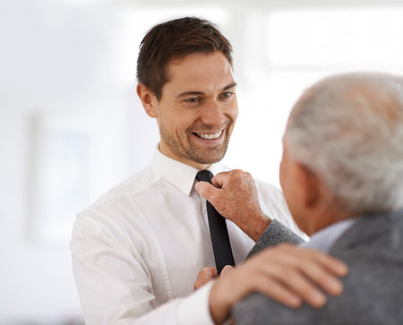 Go on and make me proud. a senior man helping to straighten a young mans tie.の写真素材