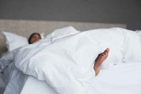 Loving this Saturday morning lie in. a young womans feet sticking out of the duvet as she sleeps.の写真素材