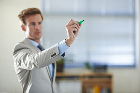 Planning for the future. a serious young business professional writing on glass with a marker.の写真素材
