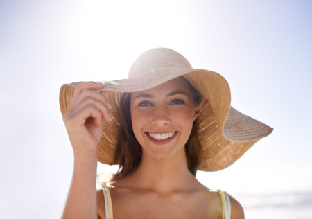 Feeling summery in her sunhat. A young woman wearing a sunhat at the beach.