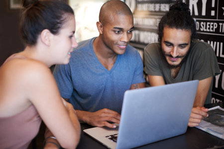 Brainstorming over their latest blog. a group of friends using a laptop in a coffee shop.