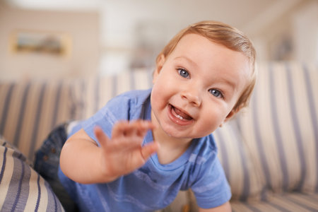 The cutest smile. an adorable little infant sitting on a sofa.