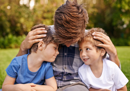 My boys mean the world to me. a father and his two little sons sitting on the grass.の写真素材