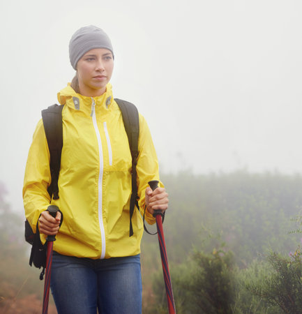 Hitting the trail on her own. a young woman hiking along a trail on an overcast day.
