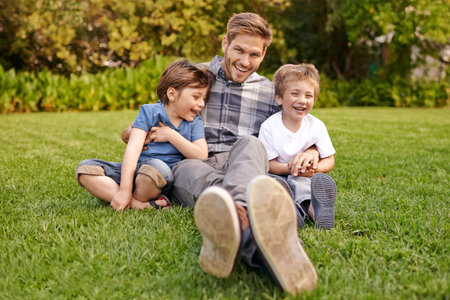 I wouldnt trade this time for anything in the world. Portrait of a father and his two little sons sitting on the grass.の写真素材