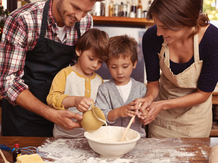 Baking as a family. Two cute little boys baking with their parents in the kitchen.