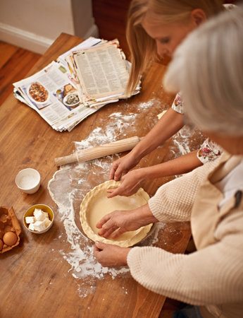 Adding the finishing touches before baking. a young woman learning baking tips from her grandmother.の写真素材