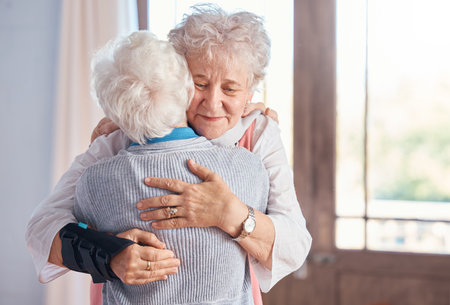 Elderly women, hug and nursing home, friends and support, comfort and care, together with bond. Senior people hugging, retirement and love with friendship in retirement home and connection.の写真素材
