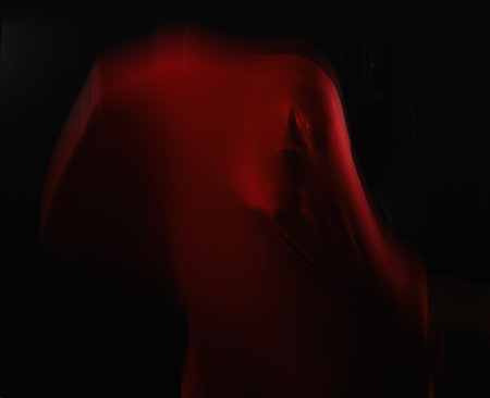 Fear personified. A human figure trapped in red fabric and struggling to break free while isolated on black.の写真素材