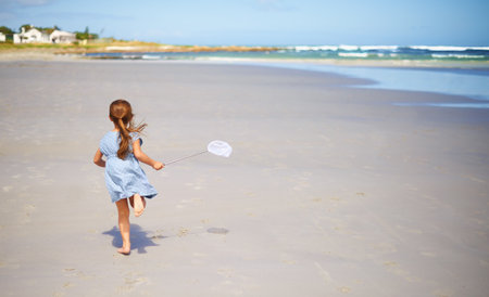Reveling in the freedom of childhood. a little girl running along the beach.の写真素材