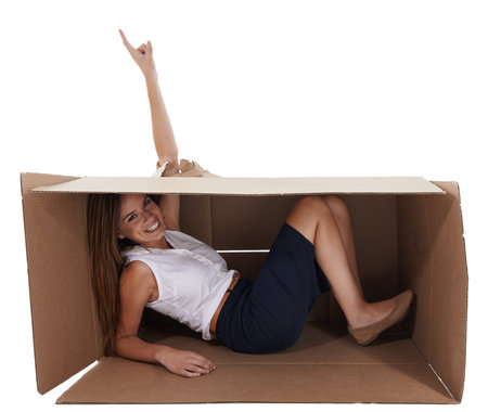 Nothings keeping her genius trapped. A young woman breaking through a cardboard box shes trapped in while isolated on white.の写真素材