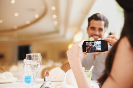 Smile for the camera, honey. A woman taking a picture of her partner while dining out at a fancy restaurant.の写真素材