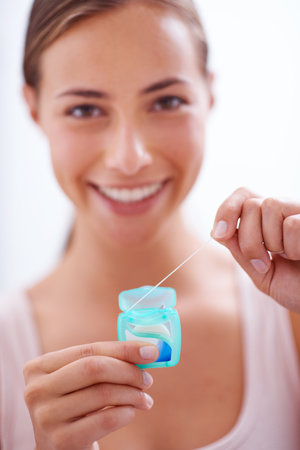 Dental hygiene is a priority. A young woman flossing her teeth.の写真素材