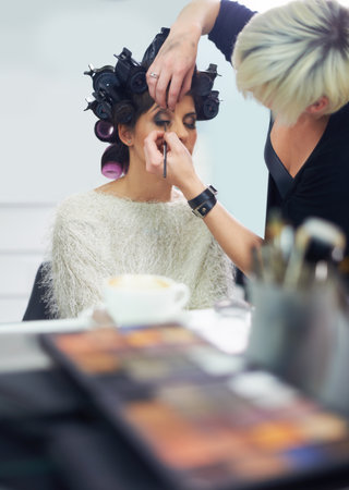 Getting ready for her big day. A young model at the hair salon having her makeup applied.の写真素材
