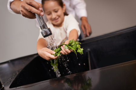 Giving her a helping hand. a little girl washing vegetables at the sink with the help of her grandfather.の写真素材