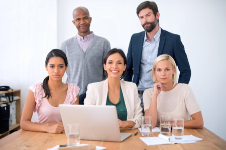 Ready to take on their latest project. A group of business people sitting a desk smiling at the...