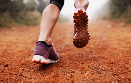 These calves were made for running. Closeup shot of a woman running on a trail on a misty morning.の写真素材