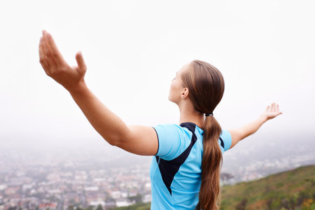 Embracing the morning. a young woman training outdoors with her arms outstretched.の写真素材