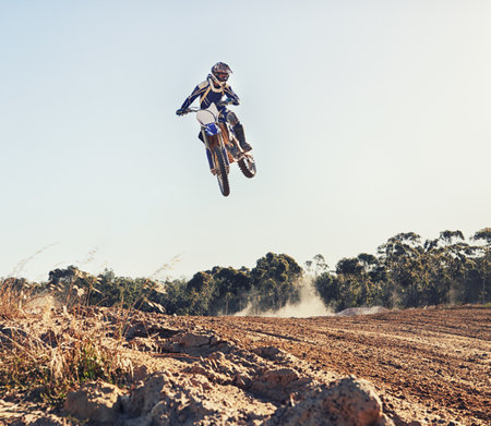 Hitting the jump at full throttle. a motocross rider coming over a jump during a race.の写真素材