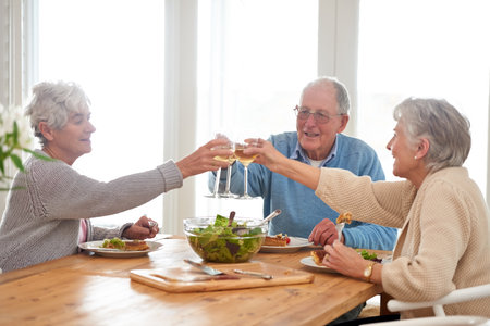 To good friends and good food. A senior man and two senior women enjoying lunch.の写真素材